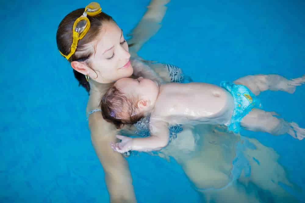 Madre con su hijo en el pecho aprendiendo a mantener la flotación